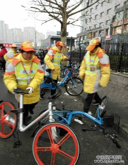 北京街头，公交志愿者帮忙摆放倒伏的共享单车。