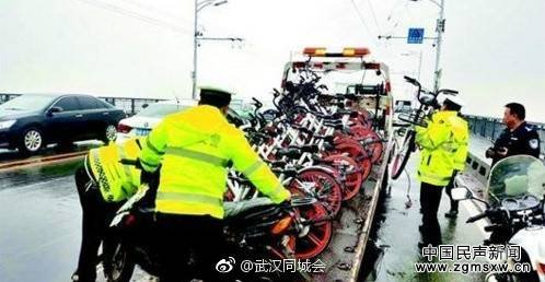 近日，50辆共享单车被乱停在武汉长江大桥上，交警雨中搬运3小时才清理好。